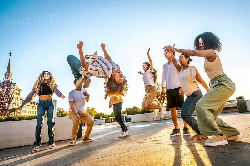 Man jumping dancing free style surrounded by multi-ethnic friends in the city during sunset