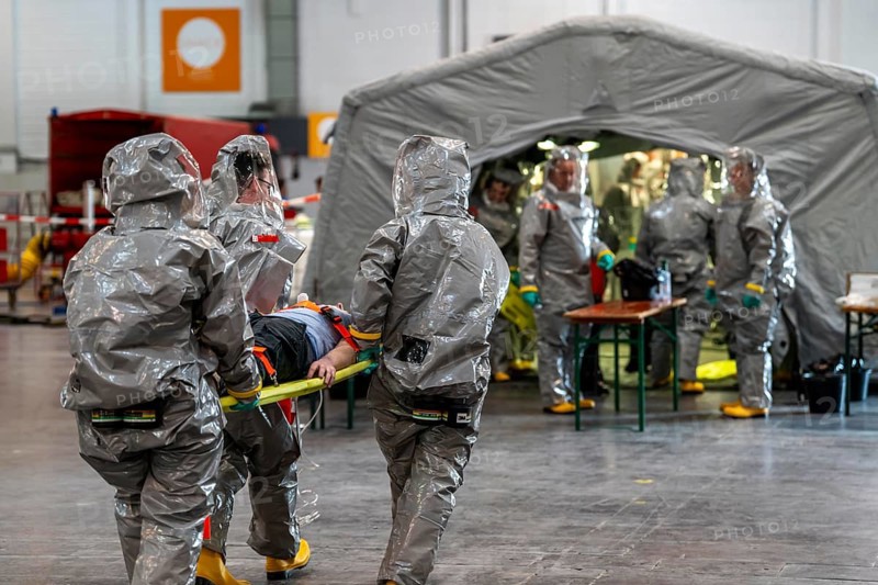 Decontamination of injured persons after an assumed accident involving hazardous substances, fire brigade and aid organisations practise setting up and operating a decontamination station, injured persons are sighted and then washed in a special shower tent to remove possible hazardous substances and chemicals in order to avoid further injuries, the emergency services wear special, ventilated protective suits, large-scale exercise by the Essen fire brigade