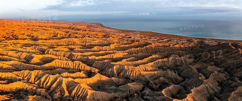 Landscape of eroded hills, badlands at sunset, Lake Issyk Kul in the background, aerial view, Canyon of the Forgotten Rivers, Issyk Kul, Kyrgyzstan, Asia