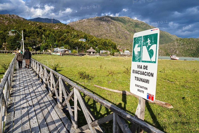 Signpost showing evacuation route in case of a tsunami, wooden boardwalk of Caleta Tortel, Aysen region, Patagonia, Chile, South America