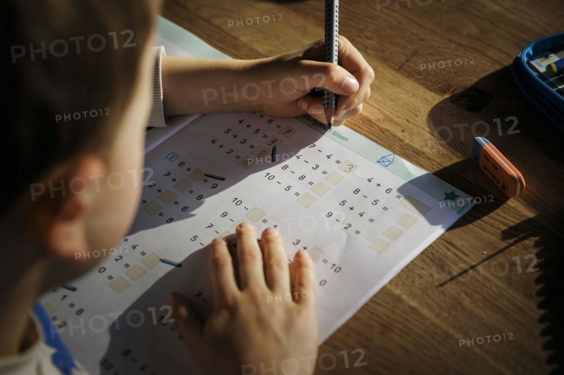 A six-year-old boy does first-grade maths homework at home in a workbook. Berlin, 13.03.2024