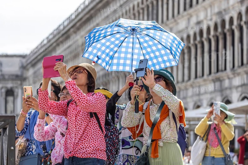 Tourists from Asia with mobile phones and parasols taking photos. Souvenir photo of St Mark's Square, Venice, Venice, Italy, Europe