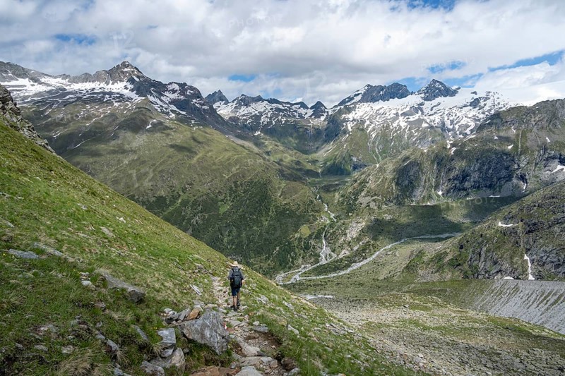 Mountaineer on a hiking trail in front of a picturesque mountain landscape, rocky mountain peaks with snow, valley Zemmgrund with Zemmbach, mountain panorama with summit Zsigmondyspitze and Großer Mörchner, Berliner Höhenweg, Zillertal Alps, Tyrol, Austria, Europe