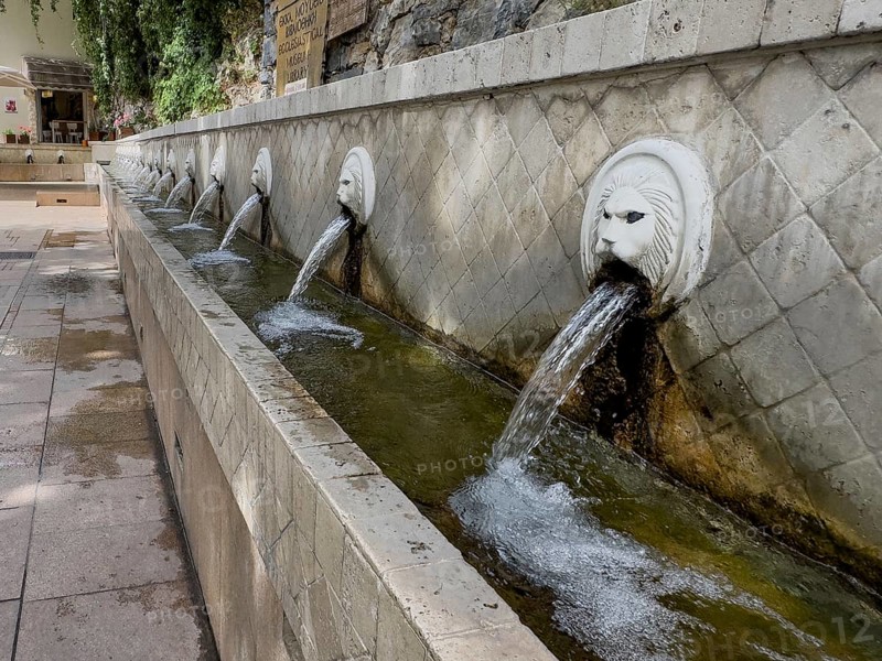Partial view of lion fountain Venetian fountain Kefalovrisi with 25 gargoyles in the shape of lion's head lion's head below collecting basin for drinking water on main square of village Spili with drinking water, Spili, Crete, Greece, Europe