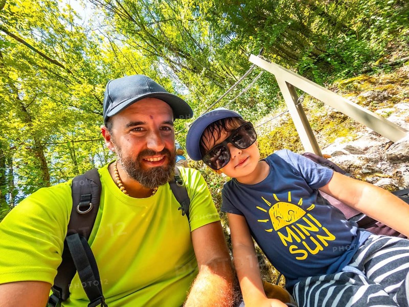 Father and son taking a selfie while hiking in a lush green forest, enjoying their summer vacation in the beautiful tolmin gorge, slovenia