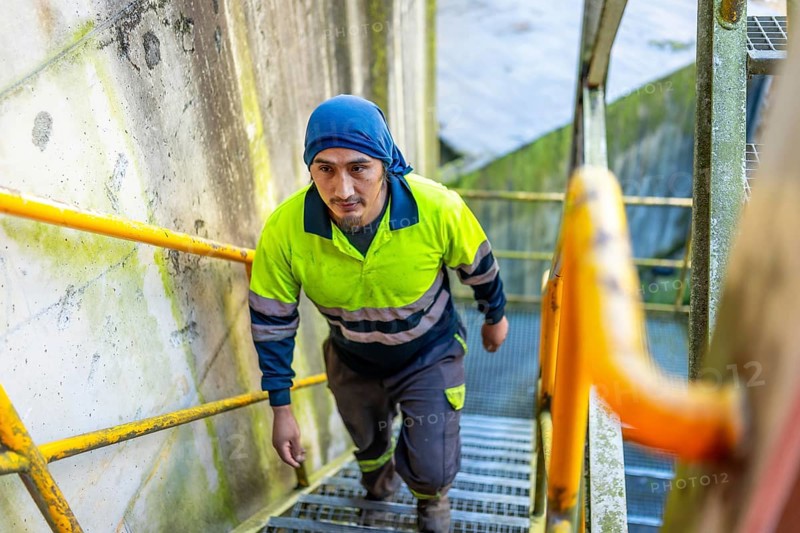 Top view of a latin man worker walking up stairs outside a recycling plant building