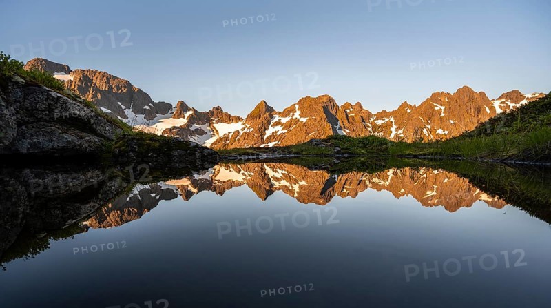 Rocky mountain peaks reflected in a small pond, mountain landscape with alpenglow at sunrise, at the Trollfjord Hytta, at the Trollfjord, Lofoten and Vesterålen, Nordland, Norway, Europe