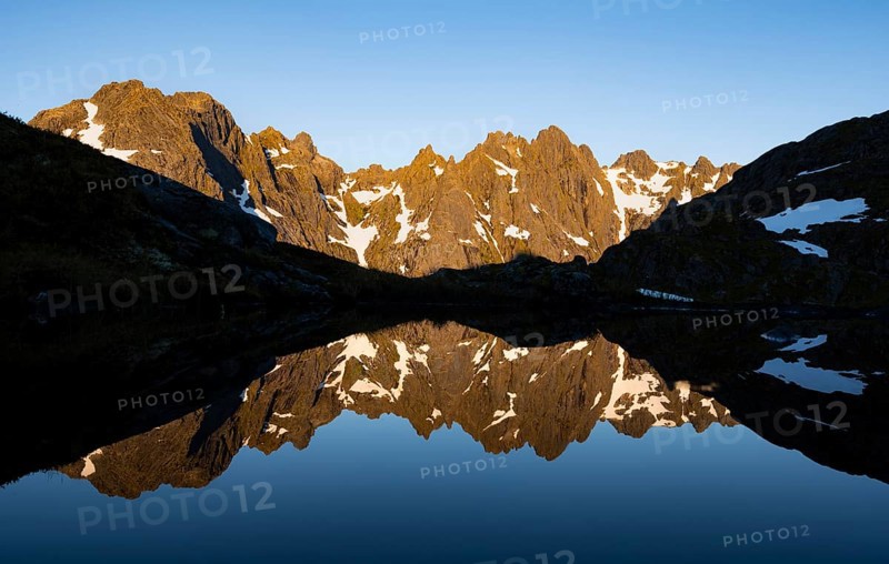 Rocky mountain peaks reflected in a small pond, mountain landscape with alpenglow at sunrise, at the Trollfjord Hytta, at the Trollfjord, Lofoten and Vesterålen, Nordland, Norway, Europe