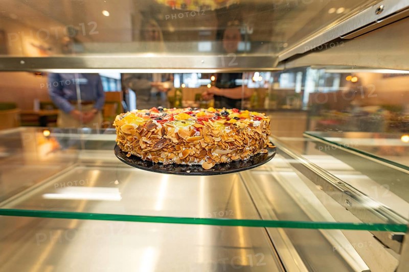 An artistically decorated cake with almond slivers and fruit in a glass display case, Cafe Kuh, Deckenpfronn, Germany, Europe
