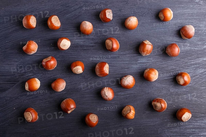 Pattern and texture made from hazelnuts on black wooden background, flat lay. top view