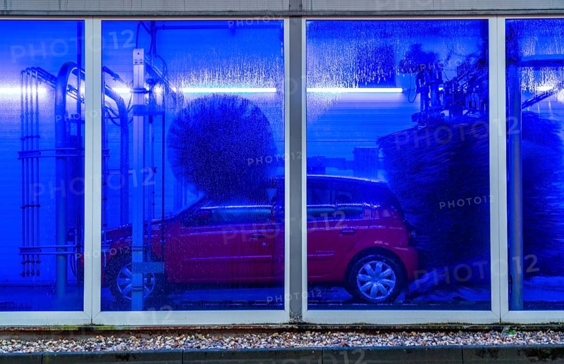 Car in an automatic car wash, car wash tunnel, cleaning foam is sprayed on, rotating brushes clean the vehicle