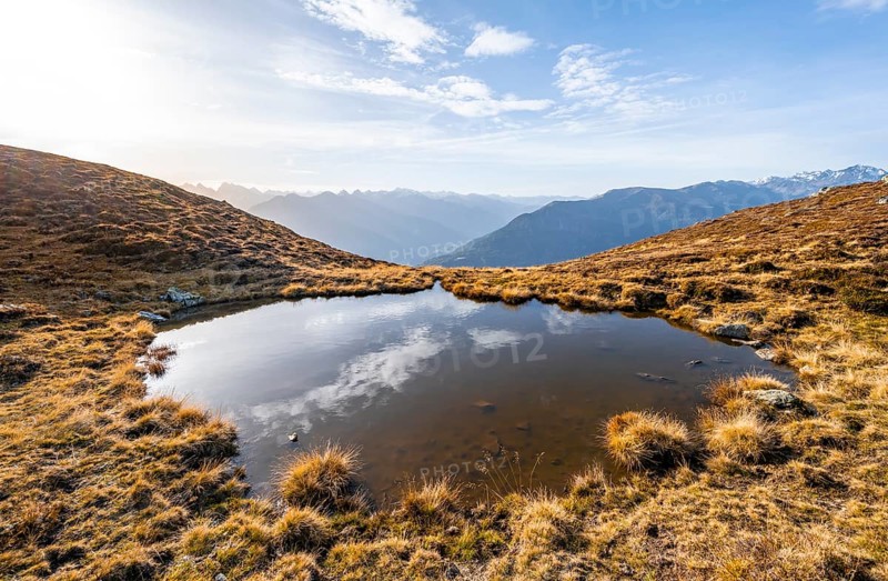 Small mountain lake on the Krahberg, sun star in the morning, mountain panorama in autumn, Venet crossing, Ötztal Alps, Tyrol, Austria, Europe