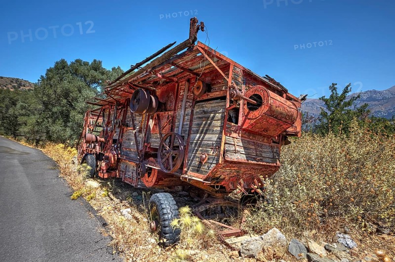 Dilapidated, rusted combine harvester next to the road under blue sky, wrecked vehicle, Crete, Greek Islands, Greece, Europe