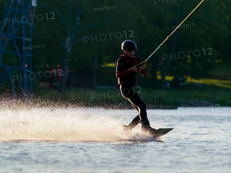 Young man with wakeboard in lake, water sports, water skiing in wakepark