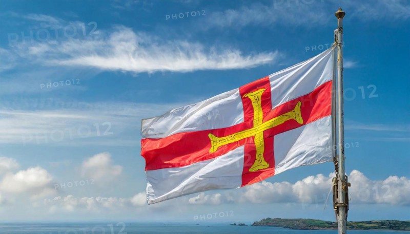 The flag of the Isle of Guernsey, Great Britain, flutters in the wind