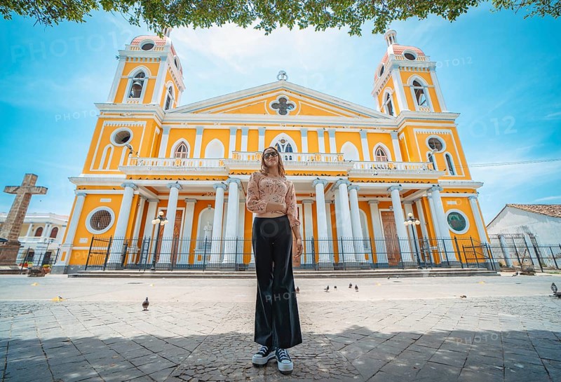 Portrait of a beautiful tourist girl in front of the cathedral in Granada, Nicaragua. Portrait of happy girl in front of a cathedral in a tourist square