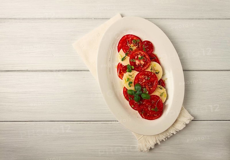 Caprese salad, Italian traditional dish, tomatoes with mozzarella cheese, basil and spices, top view, no people