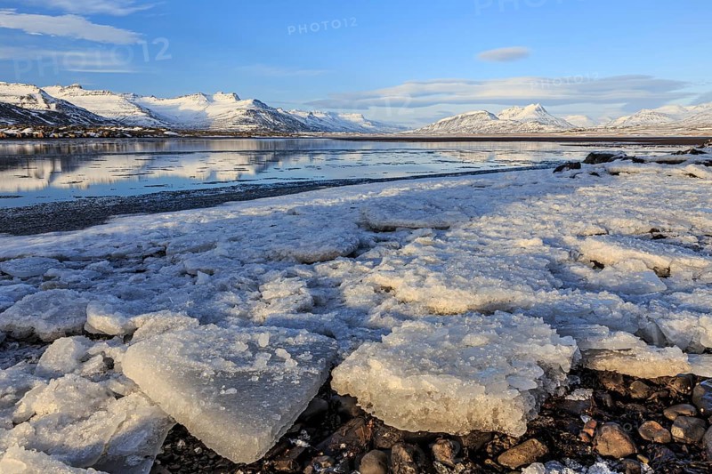 Ice floes on the shore of a fjord in front of snowy mountains, sunny, Breiddalsvik, East Fjords, Iceland, Europe