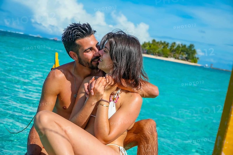 Romantic couple enjoying a kiss while relaxing on a traditional banca boat in the clear turquoise waters of siargao island, philippines