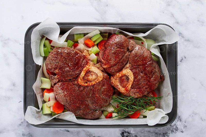 Fried meat on the bone, raw, chopped vegetables, ingredients in the oven, for cooking ossobuco, top view, no people
