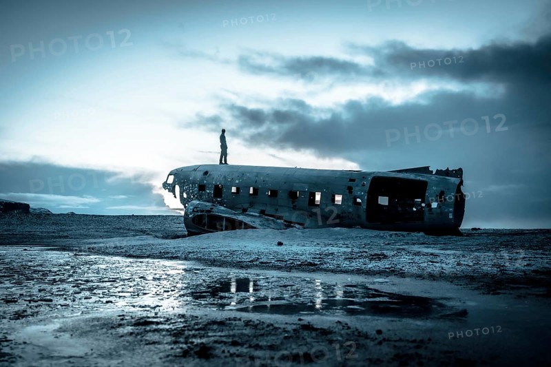A man on the crashed military plane in Solheimasandur in winter with icy ground