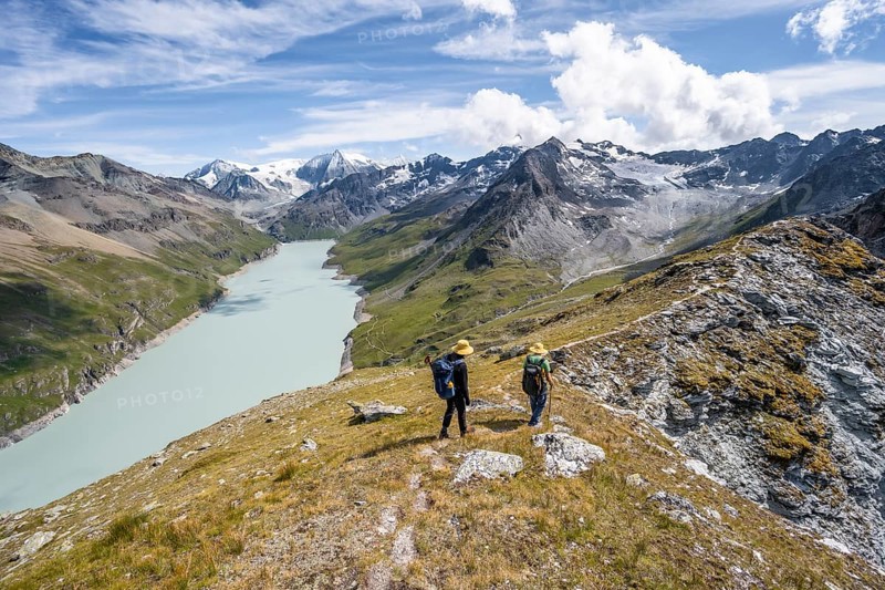 Two mountaineers on the summit of Mont de la Blana, view of a blue mountain lake, Lac des Dix reservoir, mountain peak Mont Blanc de Cheilon with glacier in the background, Hérménence, Valais Alps, Valais, Switzerland, Europe