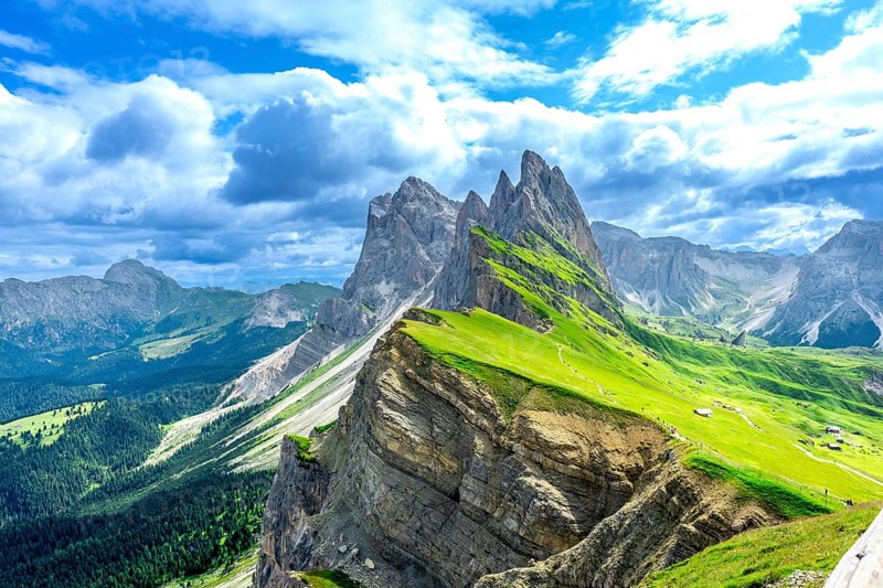 Hiking trails wind through lush green valleys beneath the majestic peaks of the seceda mountains in the italian dolomites on a sunny summer day