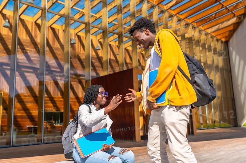 Two African female and male friends greeting each other upon arriving at the university campus