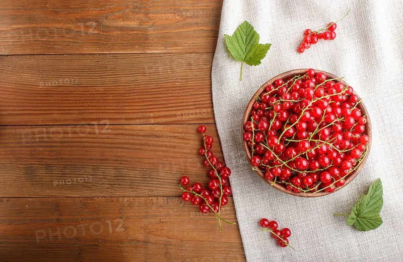 Fresh red currant in wooden bowl on wooden background. top view, flat lay, copy space
