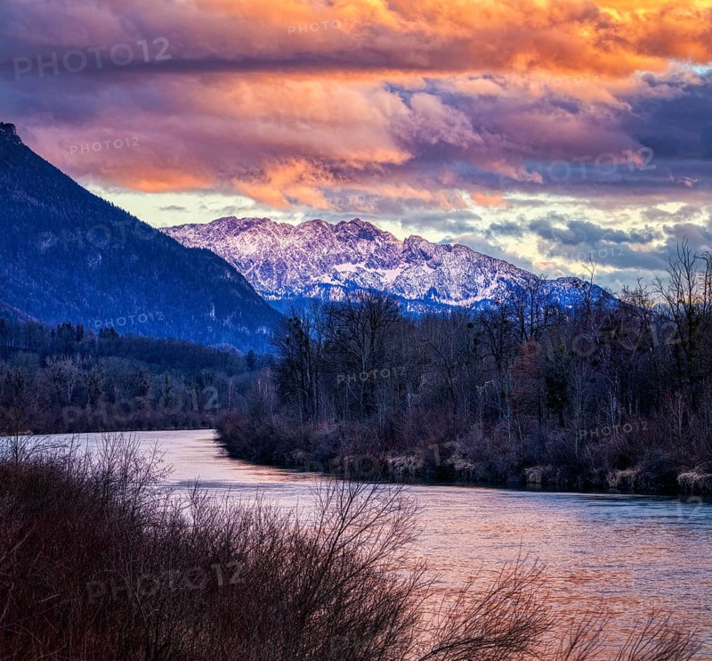 Mountain landscape at sunset with river, snow-covered peaks and dramatic cloudy sky, River Inn, near Neubeuern