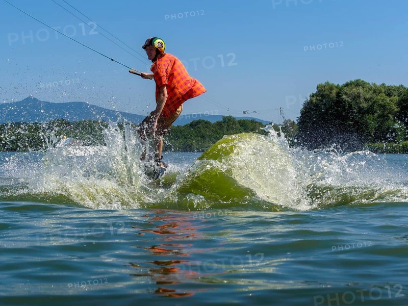 Young casual man with flapping shirt on wakeboard jumping into the lake, water ski and wakepark, Stráž pod Ralskem, Czech Republic, Europe