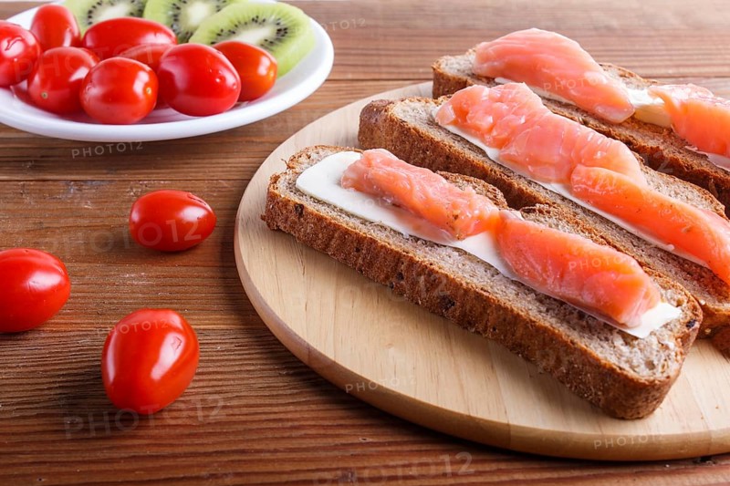 Smoked salmon sandwiches with butter on wooden background. cherry tomatoes. top view, close up