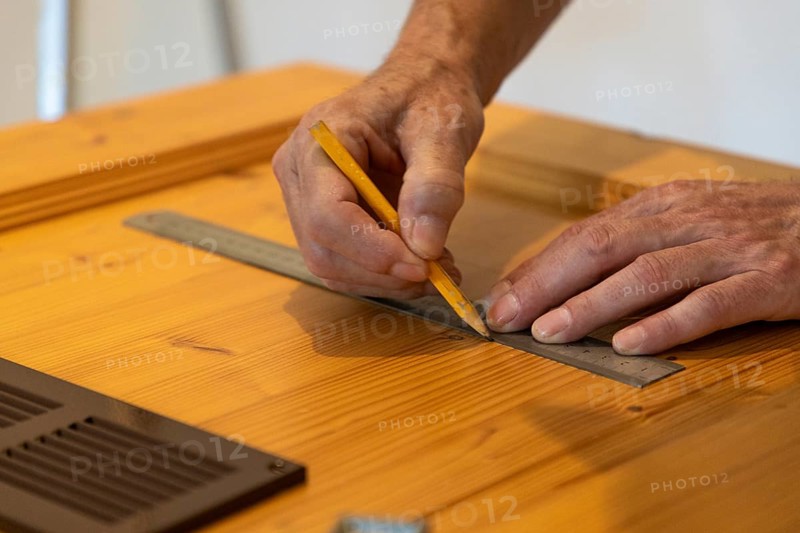 Hands using a ruler and drawing lines on wood in close-up
