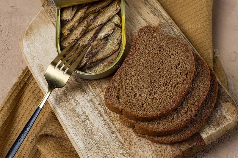 Sprats in butter, with black bread, canned smoked fish, open, close-up, top view, no people