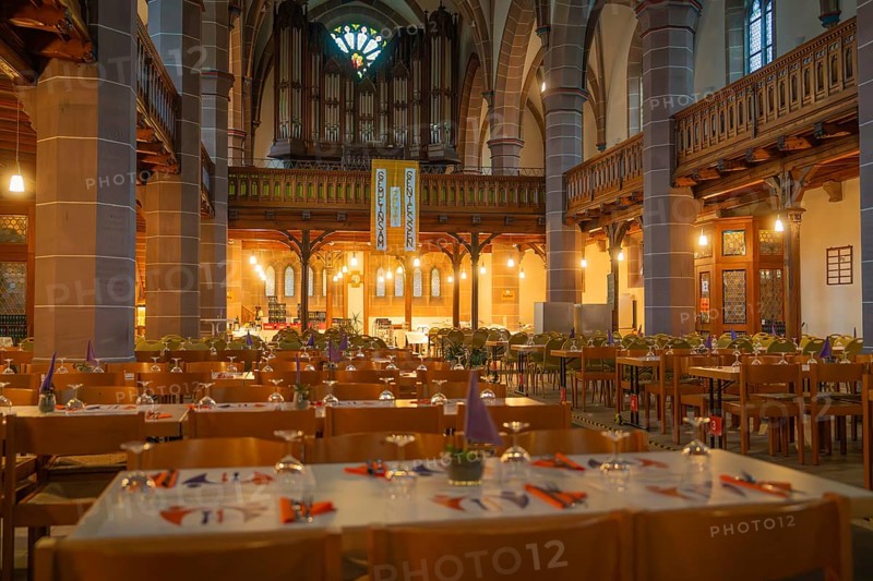 Several laid tables in a warmly lit church with organ in the background, Vesperkirche Calw, Black Forest, Germany, Europe