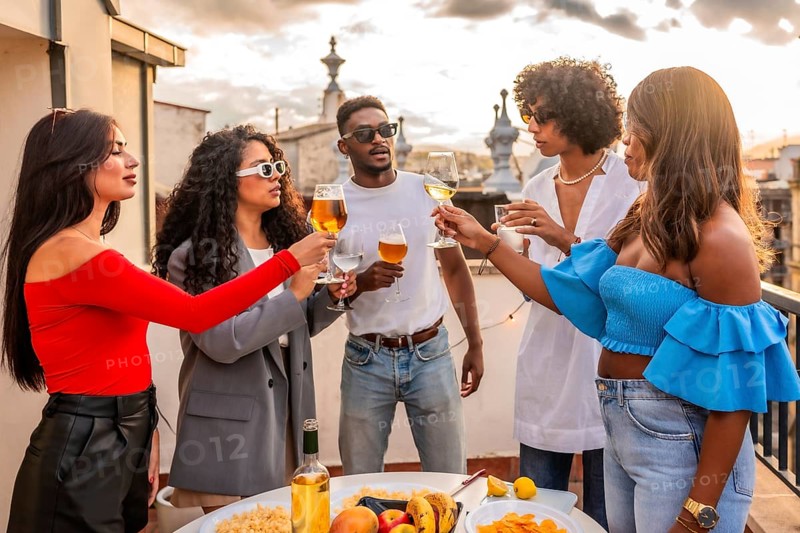 Multi-ethnic friends toasting on evening party in a city rooftop
