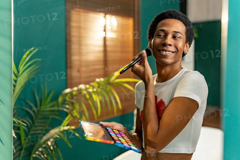 Reflection in the mirror of a transgender young latin man making up at home