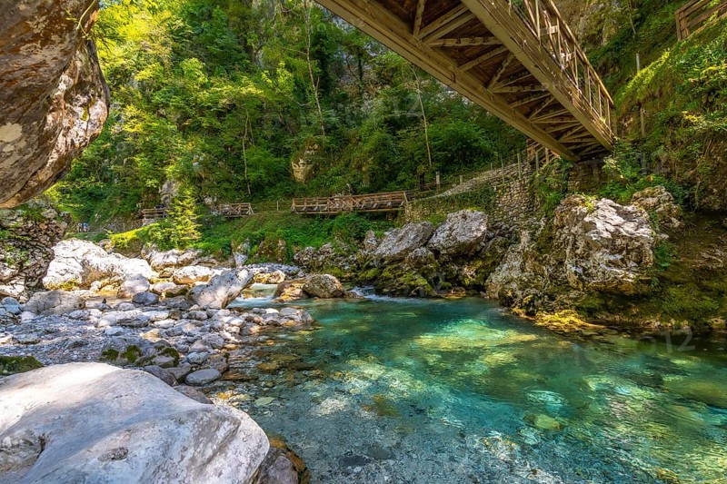 Turquoise water flowing through tolmin gorges under a wooden bridge on a summer day in slovenia