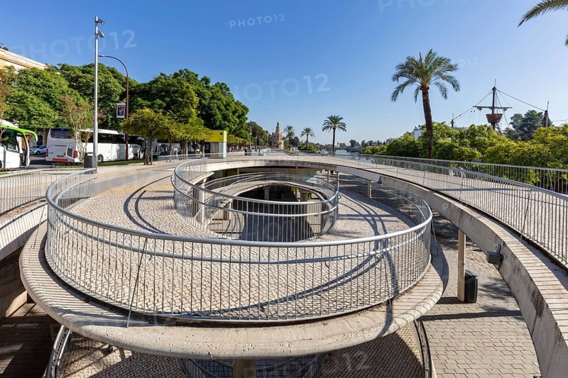 Modern pedestrian bridge with circular paths and palm trees in sunny weather, Seville