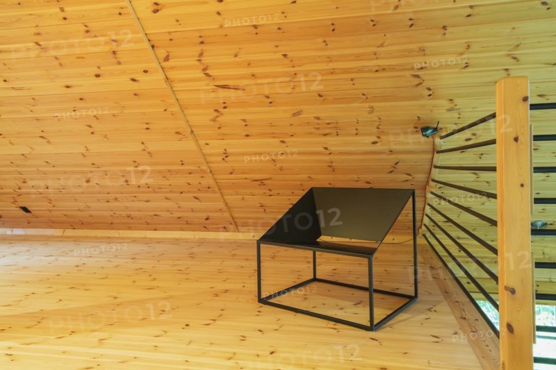 Black metal sitting chair and tubular railings with wooden post in home office set-up on mezzanine inside a piece sur piece Scots pine log home, Quebec, Canada, North America