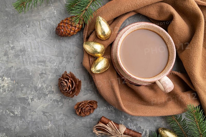 Christmas or New Year composition. Decorations, cones, cinnamon, fir and spruce branches, cup of coffee, wool scarf on a gray concrete background. Top view, close up, flat lay