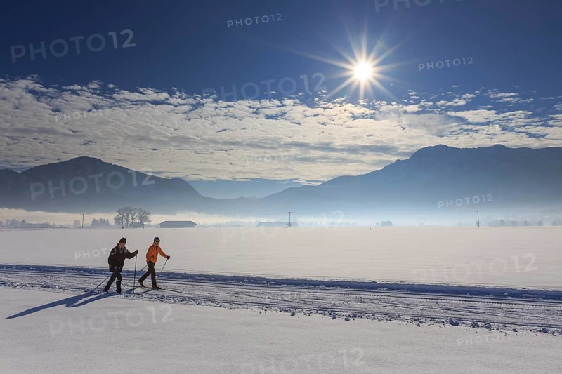 Cross-country skier, woman and man, adult, on cross-country trail in front of mountains, snow, winter, sunny, Schlehdorf, view of Jochberg and Herzogstand, Alpine foothills, Upper Bavaria, Bavaria, Germany, Europe