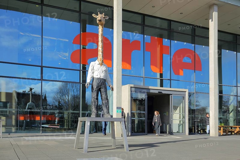 Entrance to the modern building of the ARD and ZDF broadcasting station Arte with sculpture Giraffe Man by Stephan Balkenhol, modern art, giraffe figure, giraffe man, animal figure, man figure, mythical creature, inscription, glass wall, television station, broadcasting, Strasbourg, Bas-Rhin, Alsace, France, Europe
