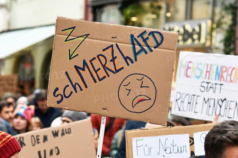 Heidelberg, Germany - February 12th 2025: Person holding up sign about CDU politian Merz and right party AfD in crowd at protest against far-right