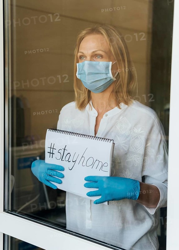Woman with medical mask holding stay home notebook window