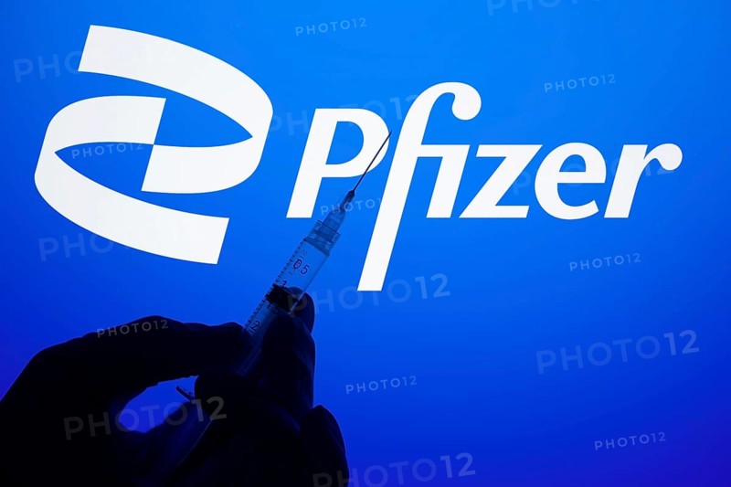 A gloved hand holding a syringe in front of the pfizer logo. Pfizer Inc. is an American multinational pharmaceutical and biotechnology corporation company