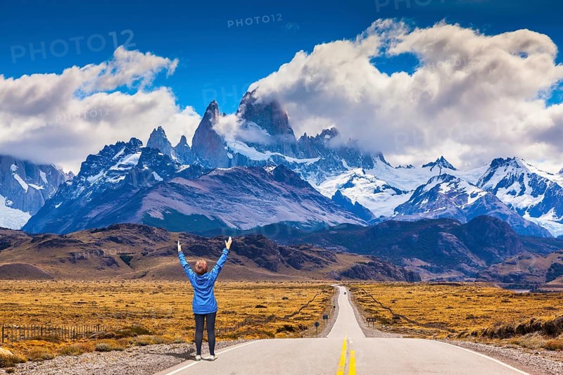 Woman delighted natural beauty raised her hands. The highway leads to the snow-capped peaks of Mount Fitzroy