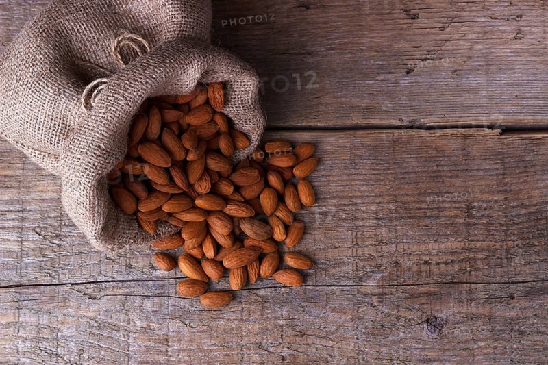 Almonds in a sack on old wooden board