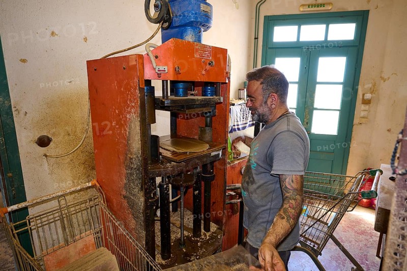 A man operates a brick press in a workshop, bricks and metal machine visible, Brickworks Patmos Cotto, Traditional brick making, Kampos, Patmos, Dodecanese, Greek Islands, Greece, Europe