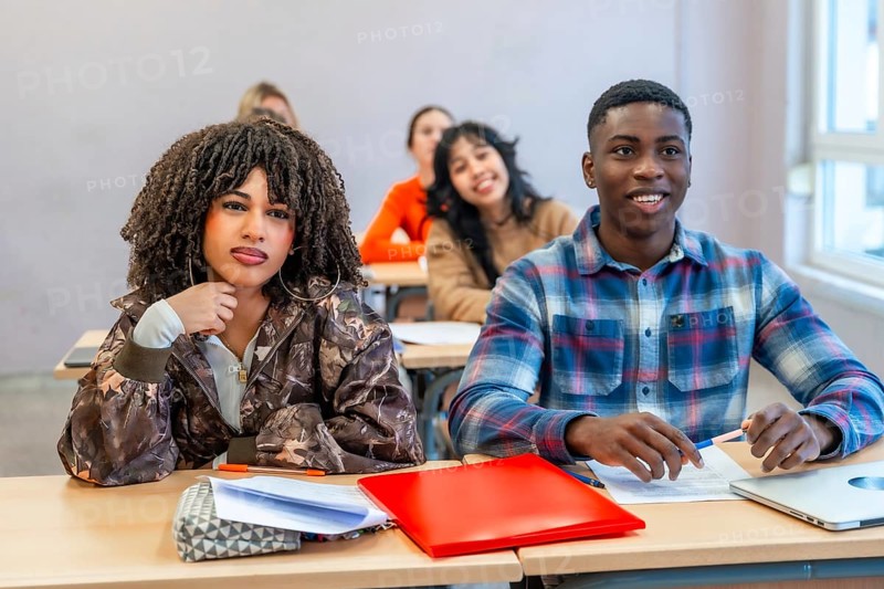 Multi ethnic students sitting at desks in a classroom, engaging with the teacher and absorbing knowledge during an interactive lesson